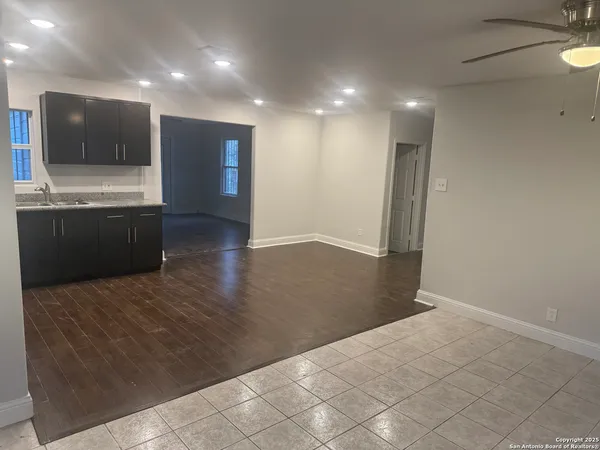 a view of an empty room with kitchen and window