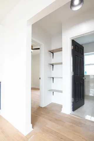 a view of an empty room with kitchen and window