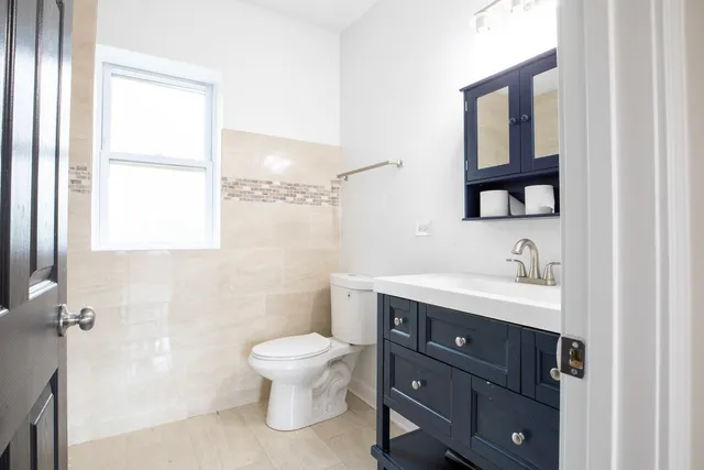 a bathroom with a toilet a sink a mirror and a window