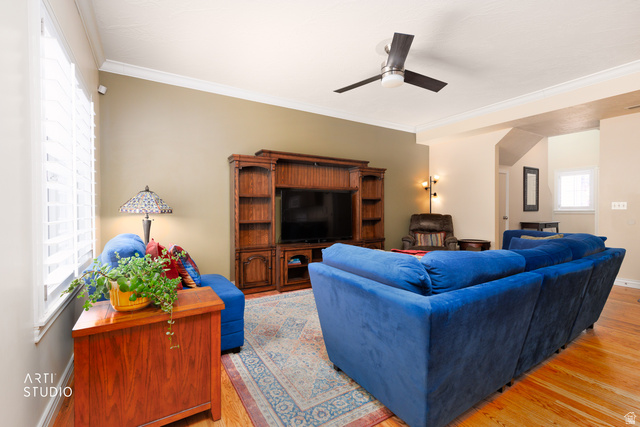6761 950 East Midvale, UT 84047 - Photo 7 of 44 Living area featuring wood-finish flooring, a built-in entertainment center with shelving, crown molding, and a ceiling fan with integrated lighting