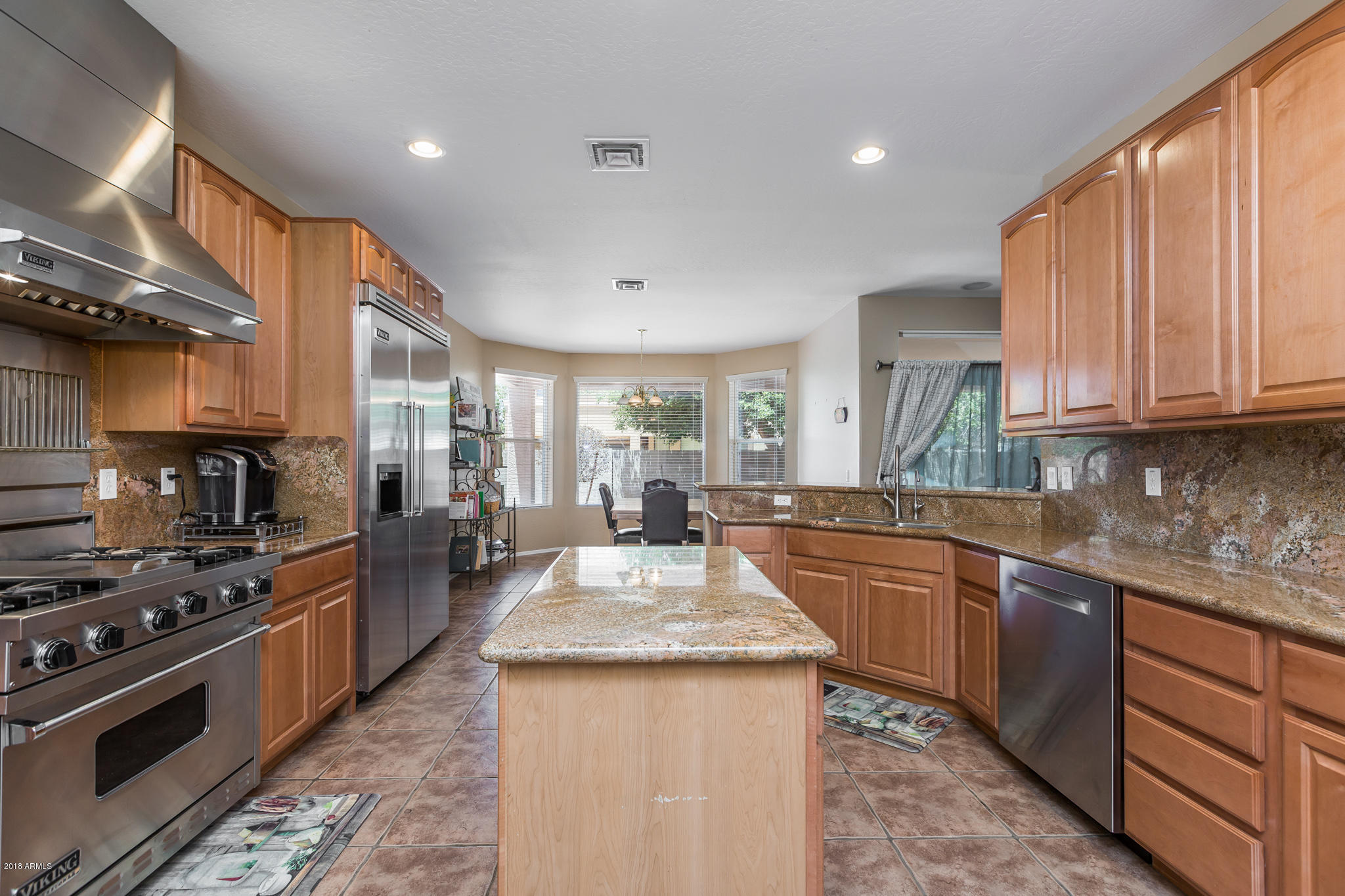 3744 East Del Rio Street Gilbert, AZ 85295 - Photo 7 of 32 a kitchen with stainless steel appliances granite countertop a stove top oven a sink dishwasher a dining table and chairs with wooden floor