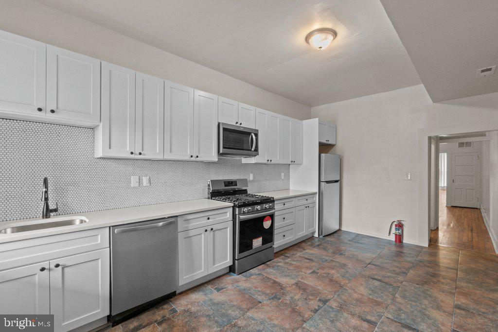 217 East Preston Street Baltimore, MD 21202 - Photo 10 of 60 a kitchen with white cabinets stainless steel appliances and sink