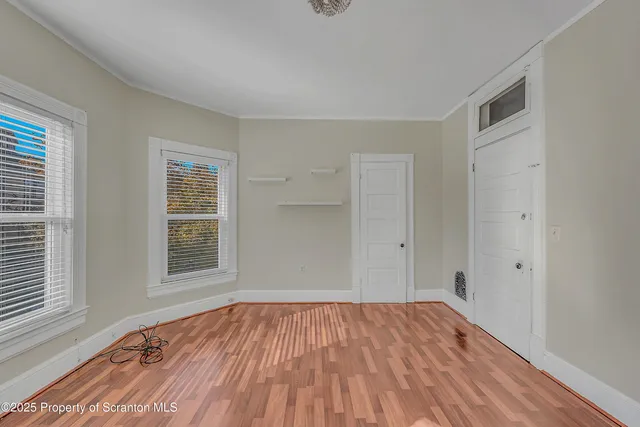 a view of empty room with wooden floor and fan