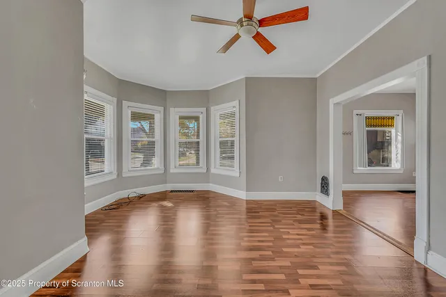 a view of empty room with wooden floor and fan