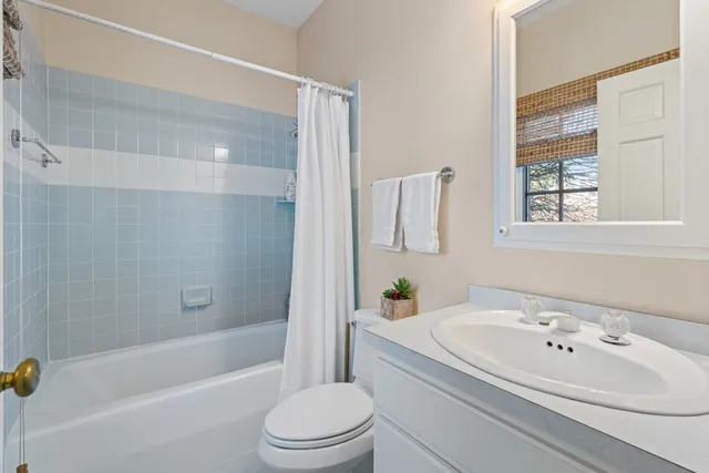 a bathroom with a granite countertop bathtub shower sink vanity and toilet