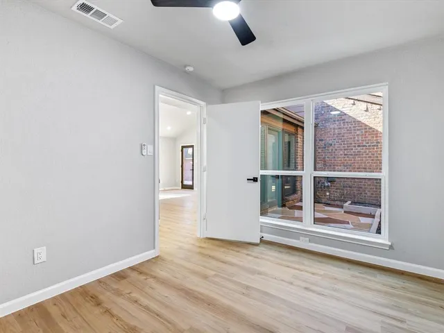 a view of an empty room with a window and wooden floor