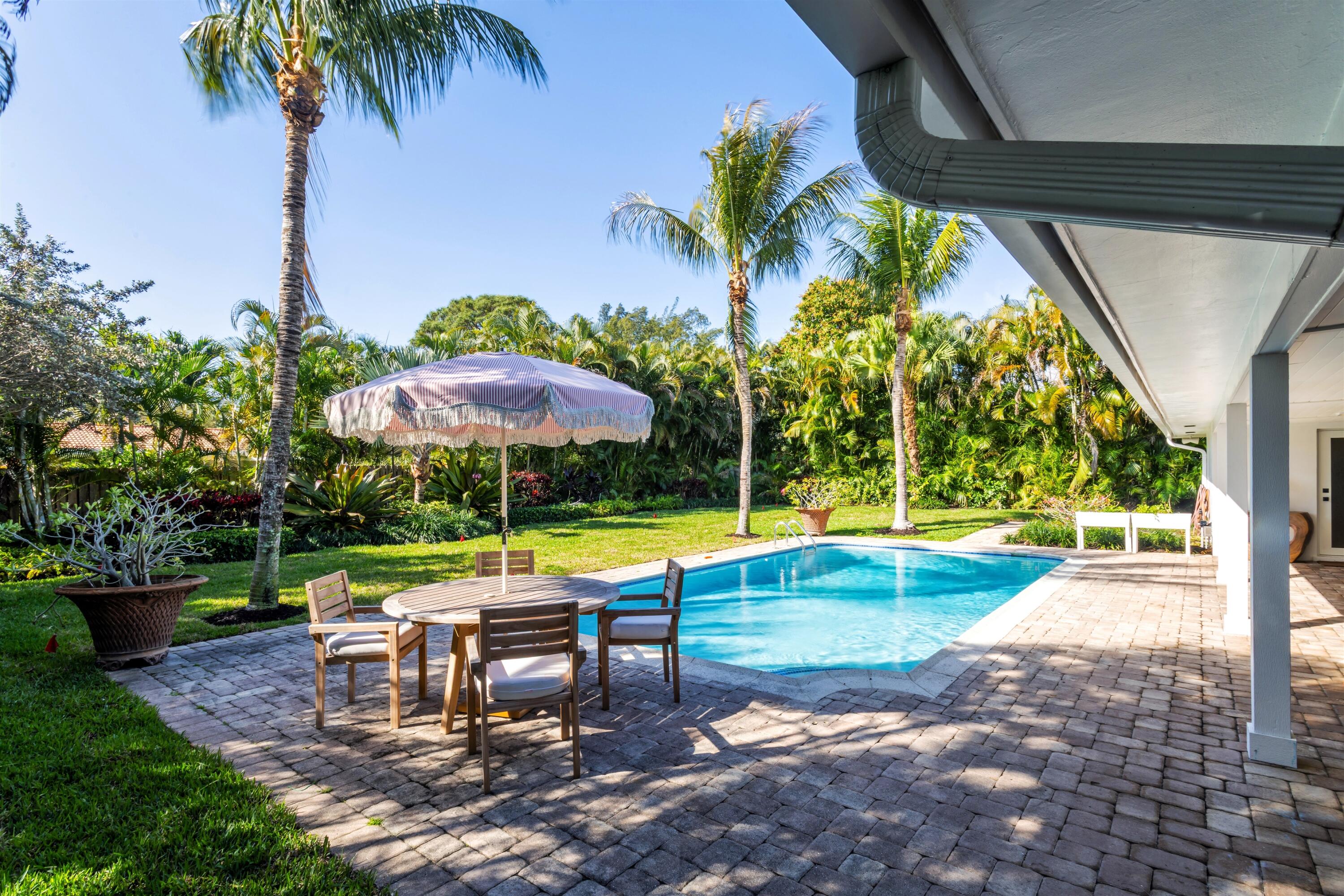2720 Cardinal Circle Gulf Stream, FL 33483 - Photo 24 of 28 a view of a swimming pool with a table and chairs under an umbrella