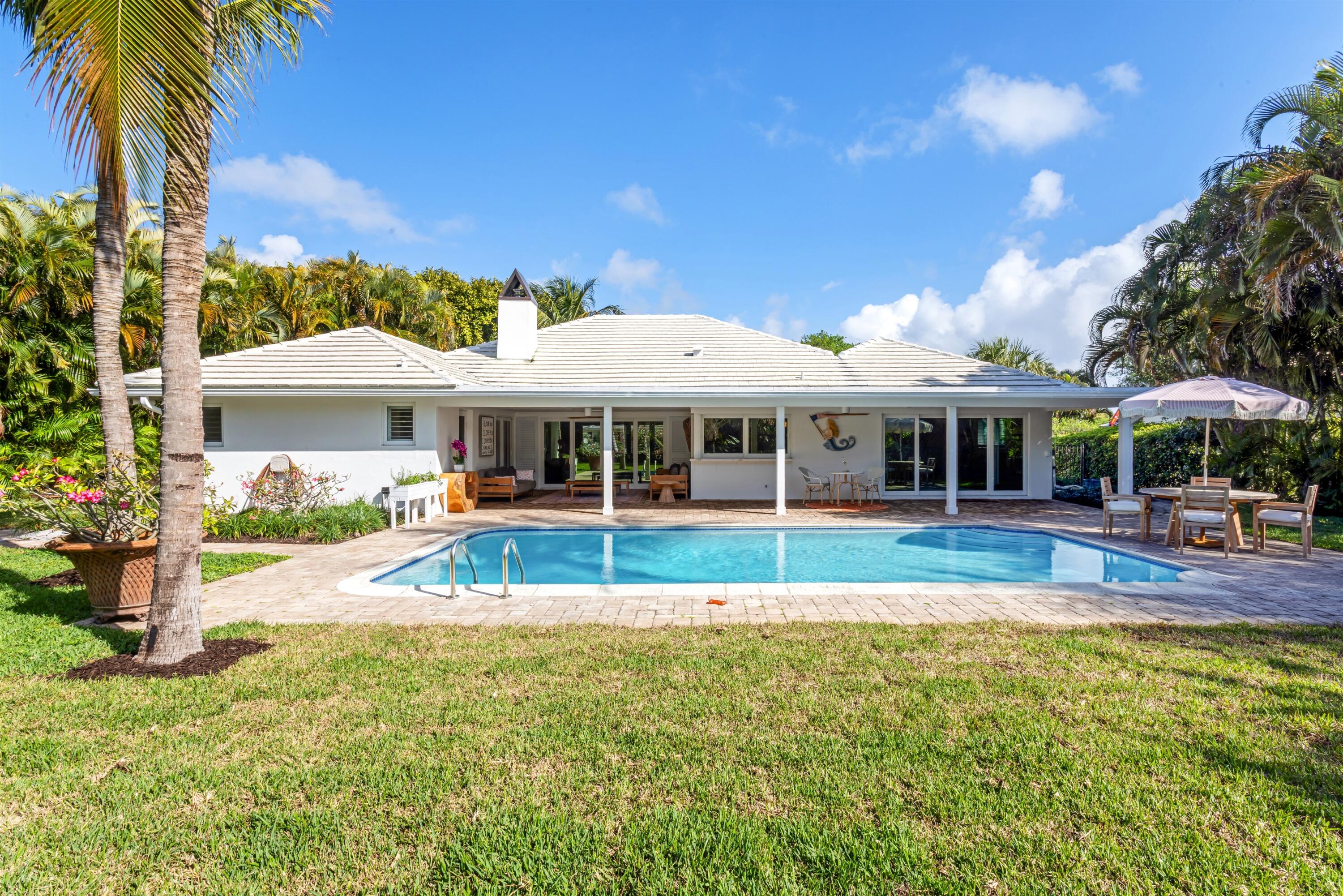 2720 Cardinal Circle Gulf Stream, FL 33483 - Photo 28 of 28 a view of a large pool with lawn chairs under an umbrella