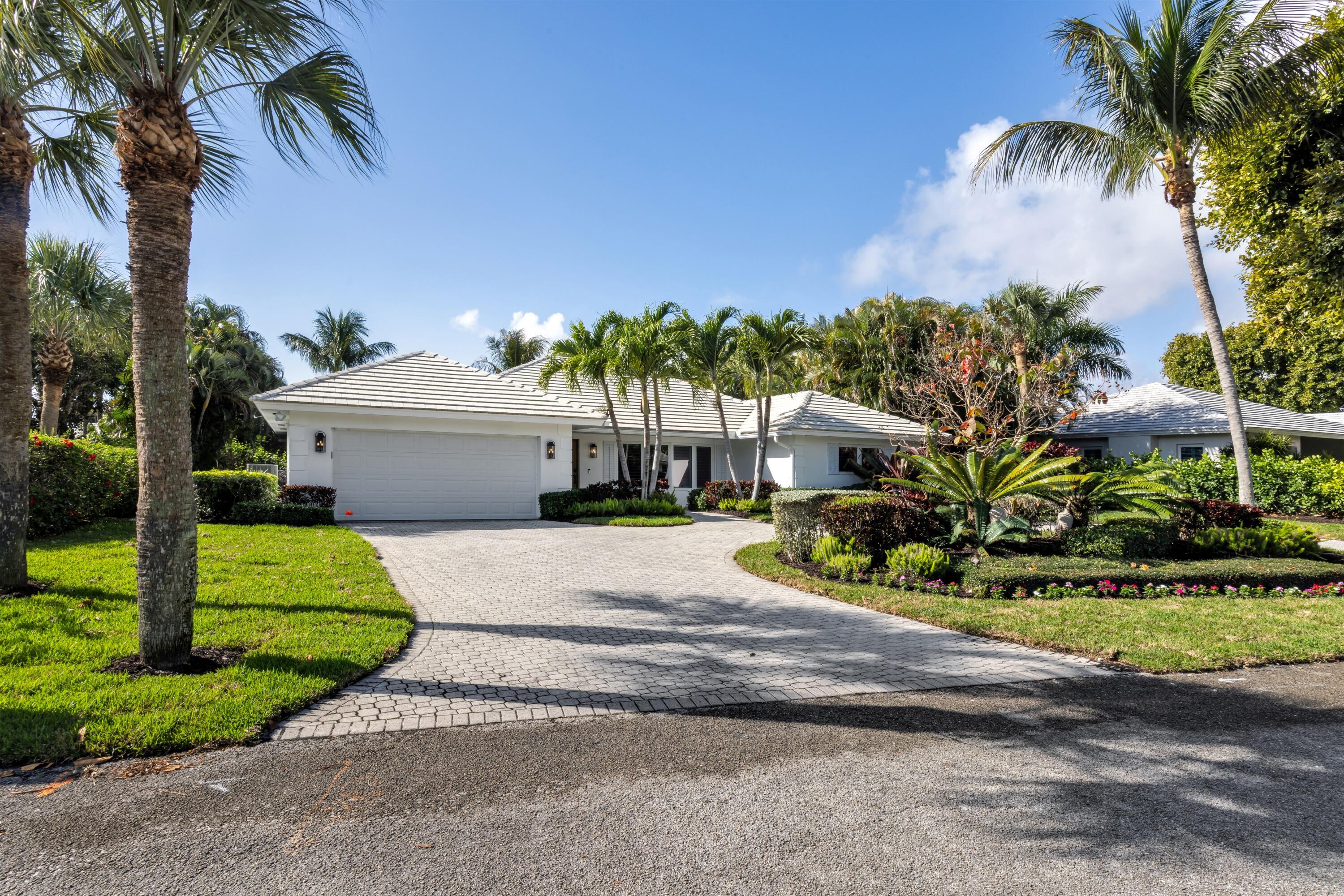 2720 Cardinal Circle Gulf Stream, FL 33483 - Photo 3 of 28 a white house with a yard and table and chairs under palm trees
