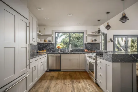 a large white kitchen with a large window and stainless steel appliances
