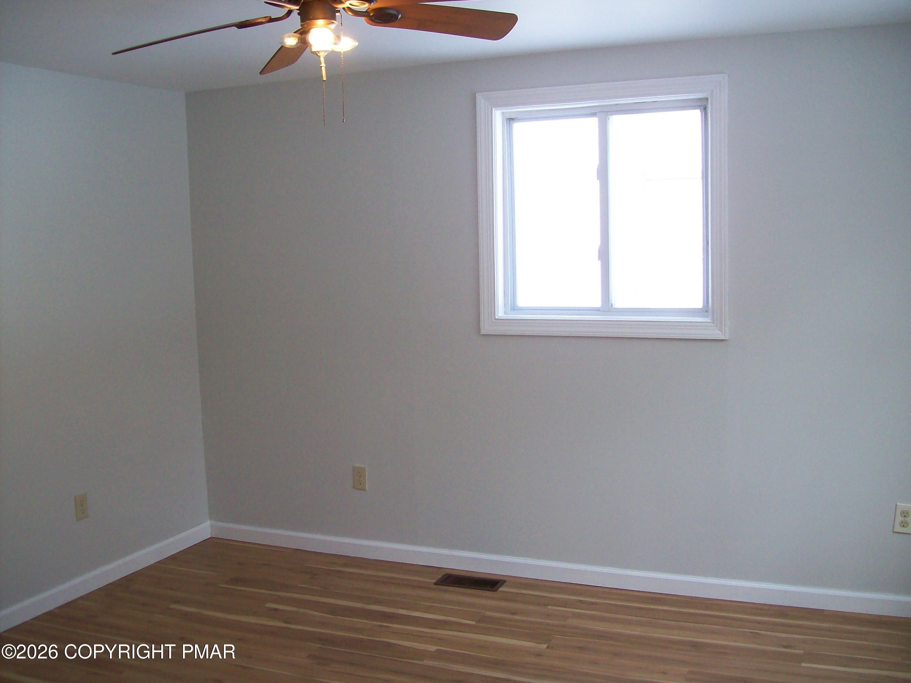 522 Apache Road East Stroudsburg, PA 18302 - Photo 18 of 23 an empty room with wooden floor chandelier fan and windows