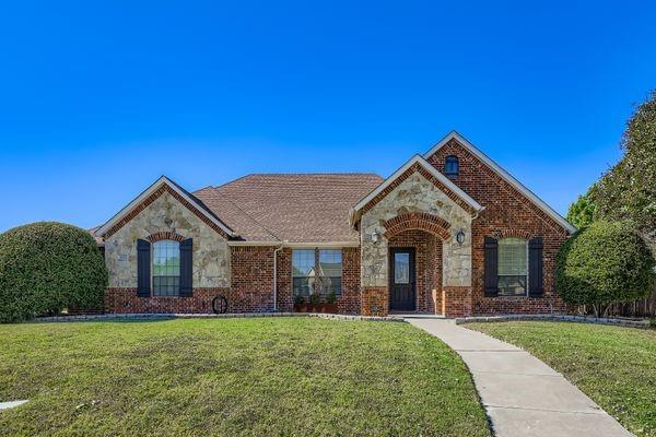 French country inspired facade with stone siding, a front lawn, and brick siding