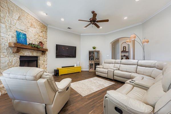 602 Christa Street Ovilla, TX 75154 - Photo 5 of 23 Living area featuring ornamental molding, dark wood-style floors, arched walkways, a stone fireplace, and ceiling fan