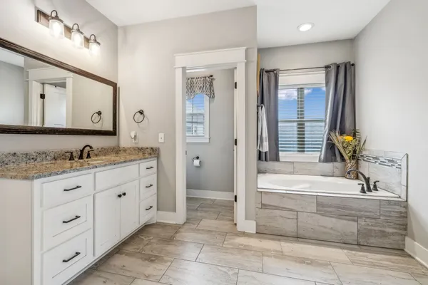 a bathroom with a granite countertop tub sink shower and mirror
