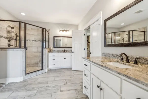 a spacious bathroom with a granite countertop sink and a mirror