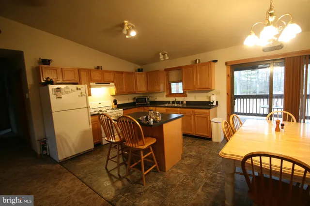 a kitchen with stainless steel appliances granite countertop a dining table chairs refrigerator and sink