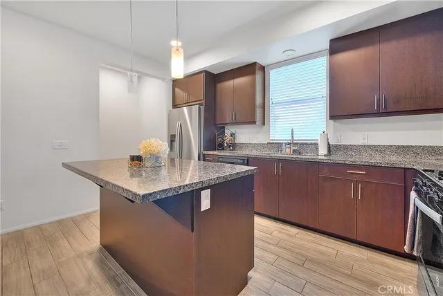 a kitchen with kitchen island granite countertop stainless steel appliances a sink stove refrigerator and cabinets
