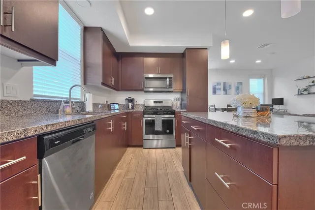 a kitchen with stainless steel appliances granite countertop a sink stove microwave and refrigerator
