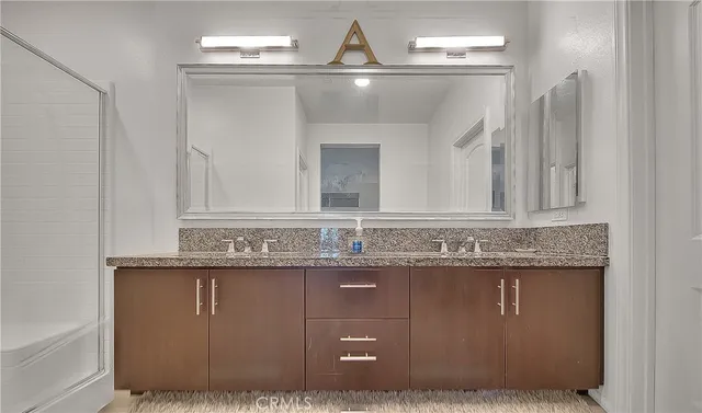 a bathroom with a granite countertop sink a mirror and shower