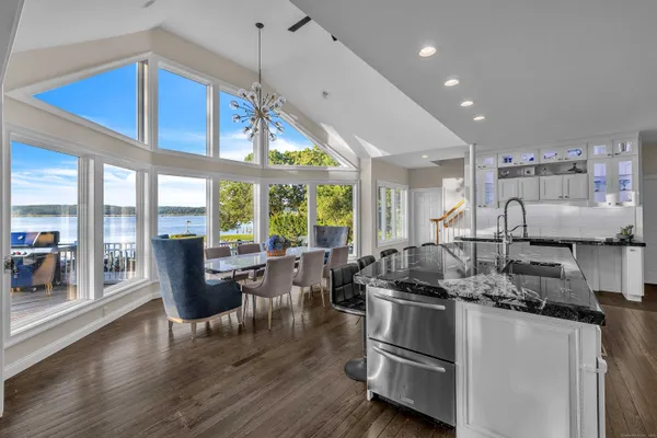 a kitchen with stainless steel appliances granite countertop a stove and a view of living room