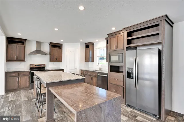 a kitchen with a refrigerator a sink and a stove top oven with wooden floor