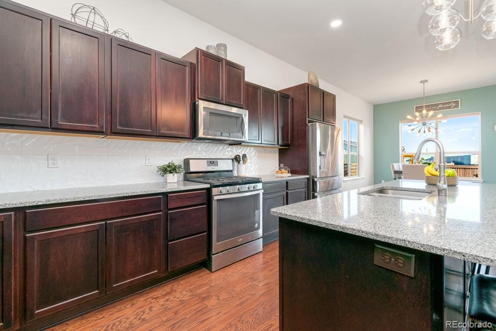 2944 Zephyr Road Fort Collins, CO 80528 - Photo 11 of 35 a kitchen with kitchen island granite countertop wooden cabinets a sink and dishwasher