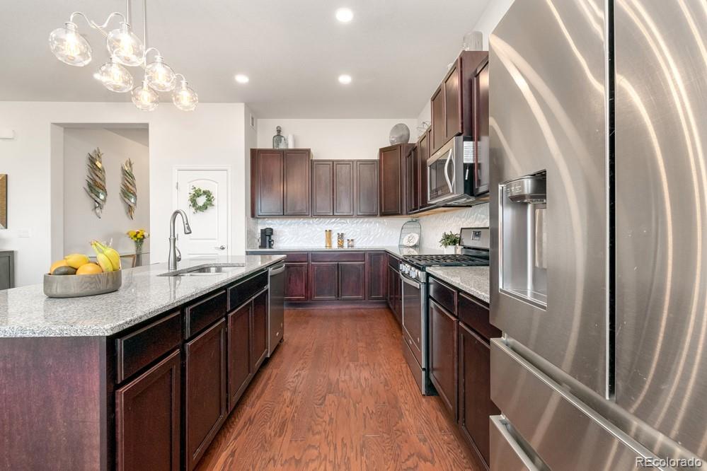 2944 Zephyr Road Fort Collins, CO 80528 - Photo 9 of 35 a kitchen with stainless steel appliances granite countertop a refrigerator a stove a sink and a microwave