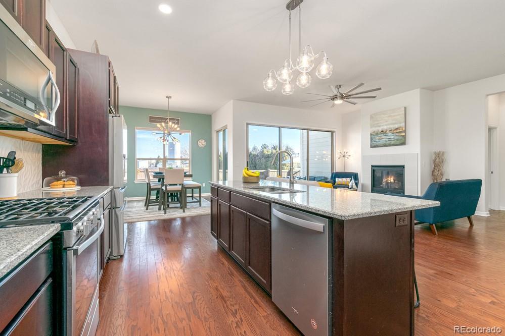 2944 Zephyr Road Fort Collins, CO 80528 - Photo 10 of 35 a kitchen with stainless steel appliances granite countertop wooden cabinets a stove top oven a sink dishwasher and a dining table with wooden floor