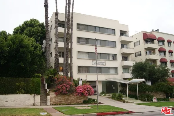 a front view of a building with a garden and plants