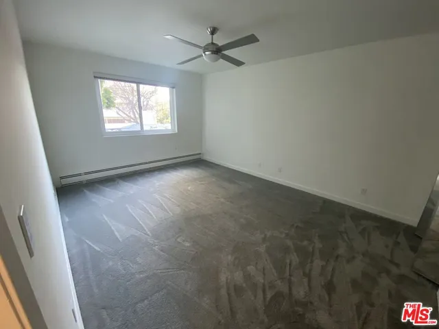 an empty room with windows and fan