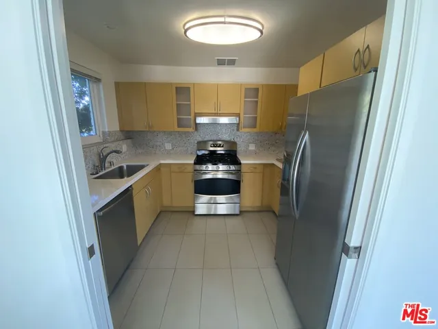 a kitchen with stainless steel appliances a refrigerator a sink a stove and cabinets