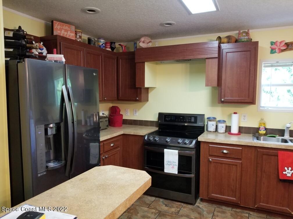 4051 Fountain Palm Road Cocoa, FL 32926 - Photo 9 of 25 a kitchen with stainless steel appliances a sink stove and refrigerator