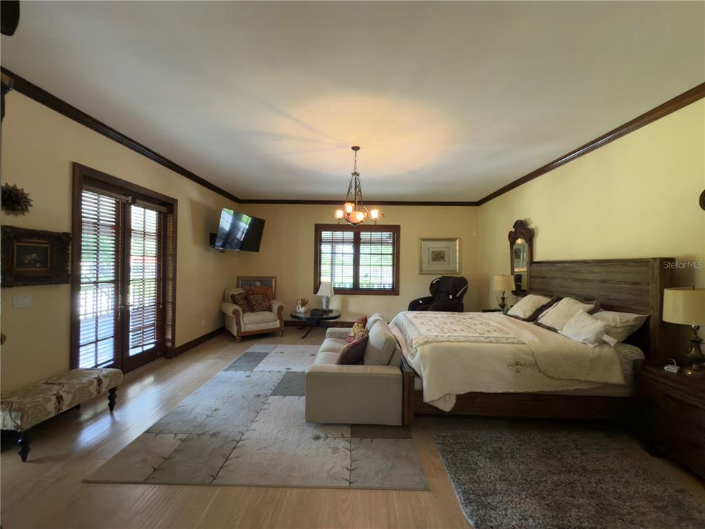 842 Hunting Club Avenue Clewiston, FL 33440 - Photo 15 of 34 a spacious bedroom with a bed a couch and large window