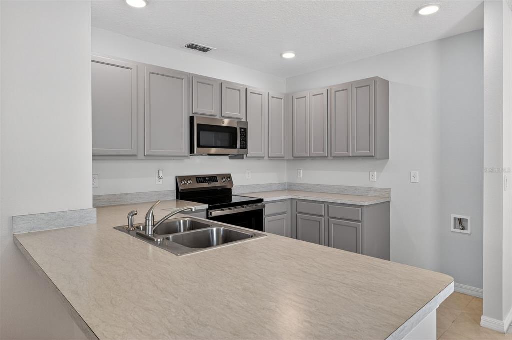 349 Honey Bell Road Winter Haven, FL 33880 - Photo 16 of 29 a kitchen with a sink a stove a microwave and wooden cabinets