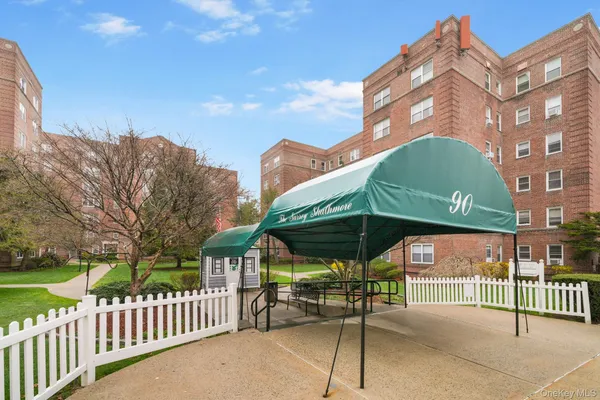 a view of a brick house with a yard and table and chairs under an umbrella