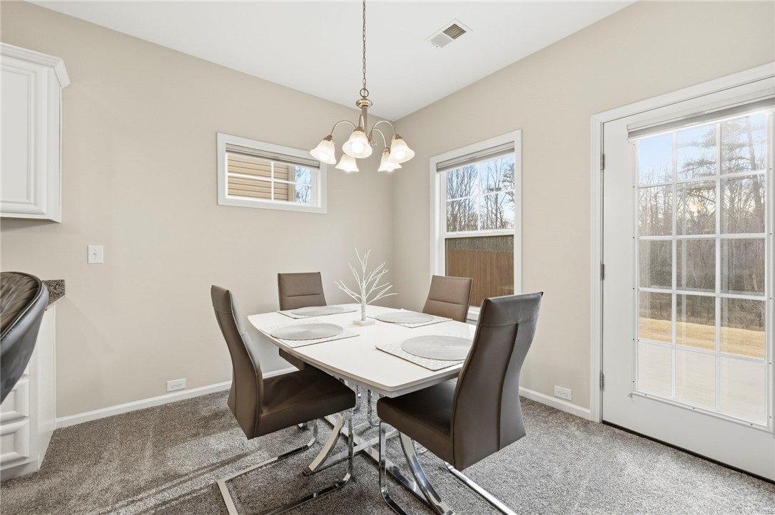 121 Wheaton Court Simpsonville, SC 29680 - Photo 18 of 40 This bright dining area features carpet flooring and ample natural light from windows and a glass-paned door.