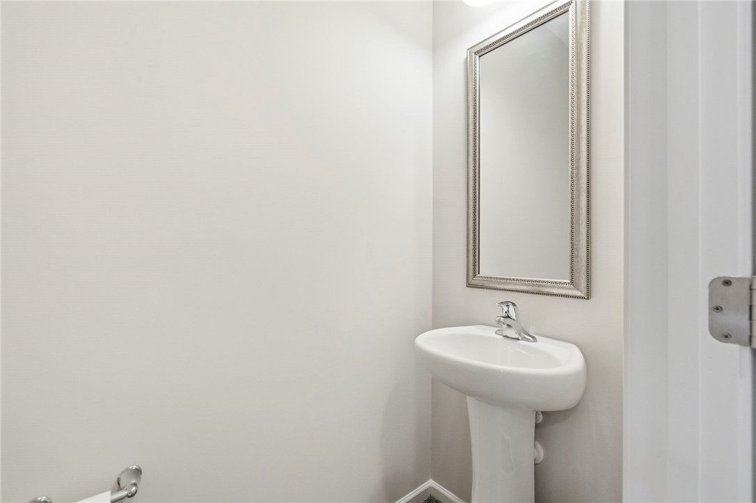 121 Wheaton Court Simpsonville, SC 29680 - Photo 20 of 40 This sleek bathroom features a contemporary pedestal sink and a decorative mirror, blending functionality with modern design.