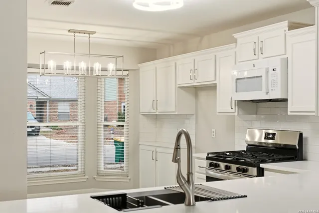 a kitchen with stainless steel appliances granite countertop a stove a refrigerator and a white cabinets