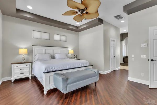 a kitchen with stainless steel appliances kitchen island granite countertop a refrigerator a stove a sink and white cabinets with wooden floor