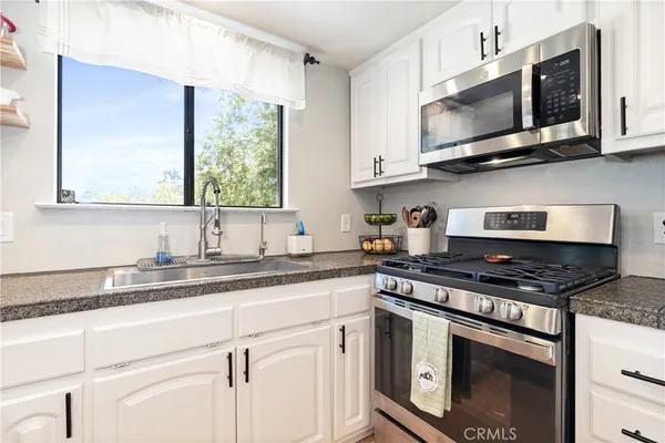 a kitchen with stainless steel appliances granite countertop white cabinets granite counter tops and a window