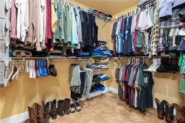a view of walk in closet with clothes and shoes
