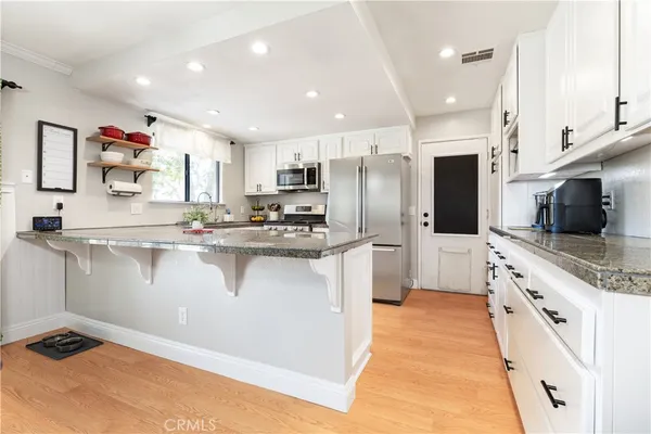 a kitchen with kitchen island granite countertop a sink a counter top space stainless steel appliances and cabinets