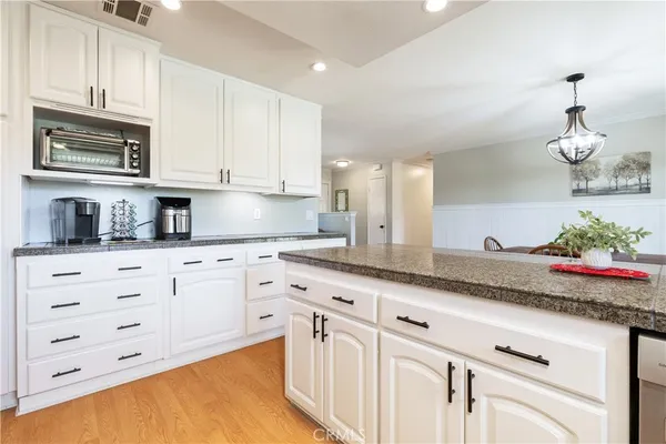 a kitchen with granite countertop white cabinets and stainless steel appliances