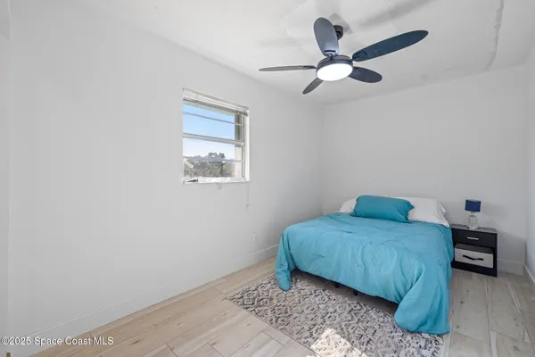 a bedroom with a bed and a chandelier fan