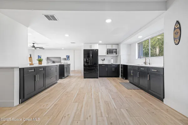 a large kitchen with stainless steel appliances granite countertop a lot of counter space and wooden floors