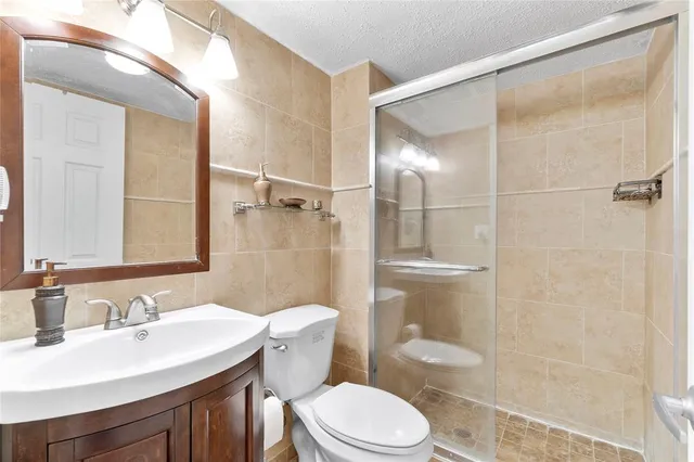 a bathroom with a sink toilet a mirror and shower
