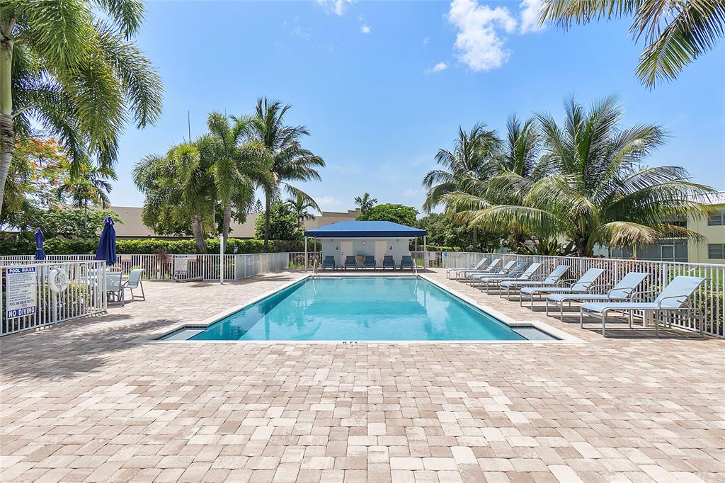 9856 Marina Boulevard, Unit 1311 Boca Raton, FL 33428 - Photo 22 of 26 a view of a swimming pool with a chair and palm trees