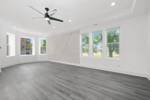 a view of empty room with wooden floor and fan