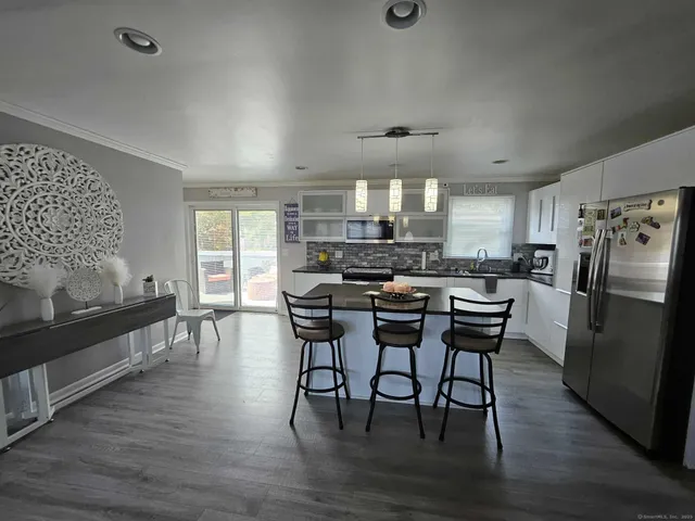 a kitchen with stainless steel appliances a dining table chairs stove and refrigerator