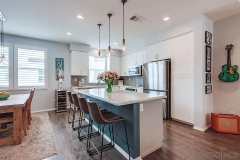 a kitchen with stainless steel appliances granite countertop a sink a stove a refrigerator and island with wooden floor